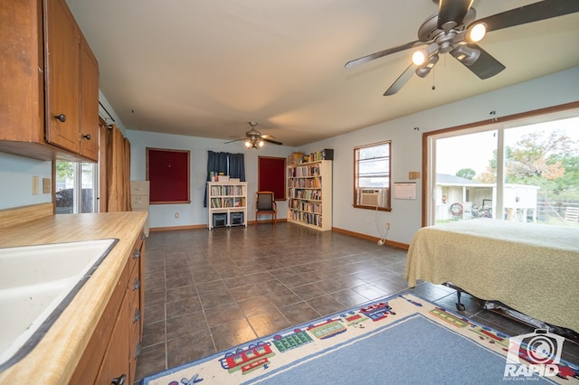 bedroom featuring cooling unit, baseboards, a sink, and a ceiling fan