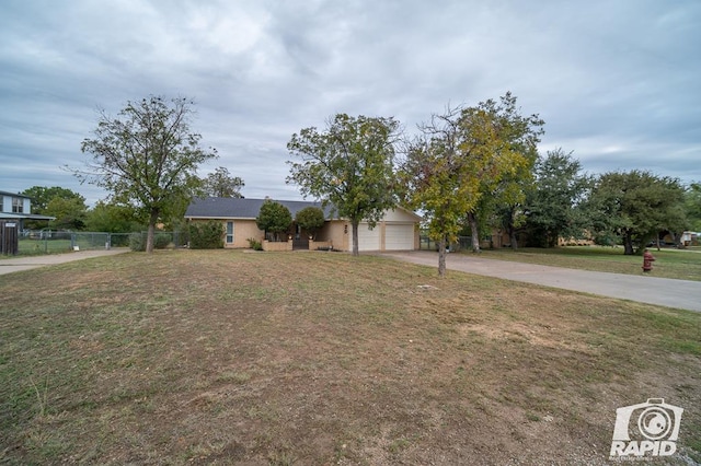 view of front facade with an attached garage, driveway, fence, and a front lawn