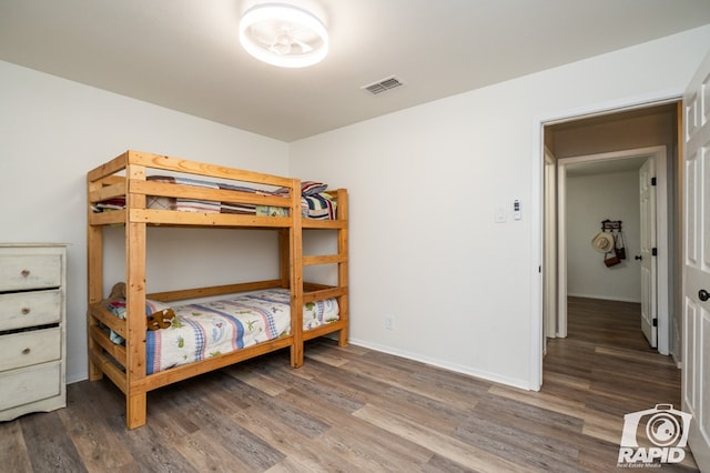 bedroom with visible vents, baseboards, and wood finished floors