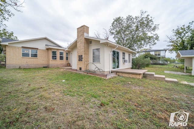 rear view of property featuring a yard, brick siding, cooling unit, and a chimney