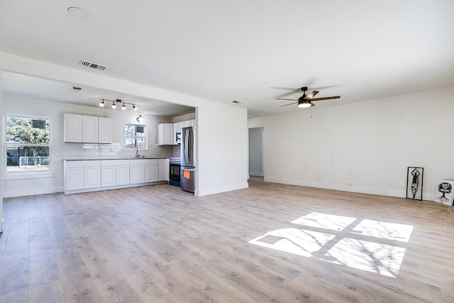 unfurnished living room featuring ceiling fan, sink, and light hardwood / wood-style floors