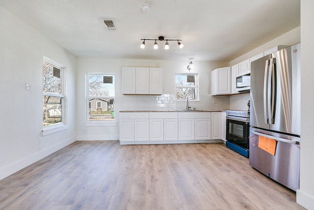 kitchen with white cabinetry, decorative backsplash, light hardwood / wood-style flooring, and appliances with stainless steel finishes