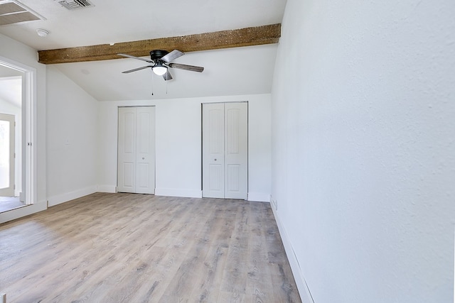 unfurnished bedroom featuring lofted ceiling with beams, ceiling fan, two closets, and light wood-type flooring