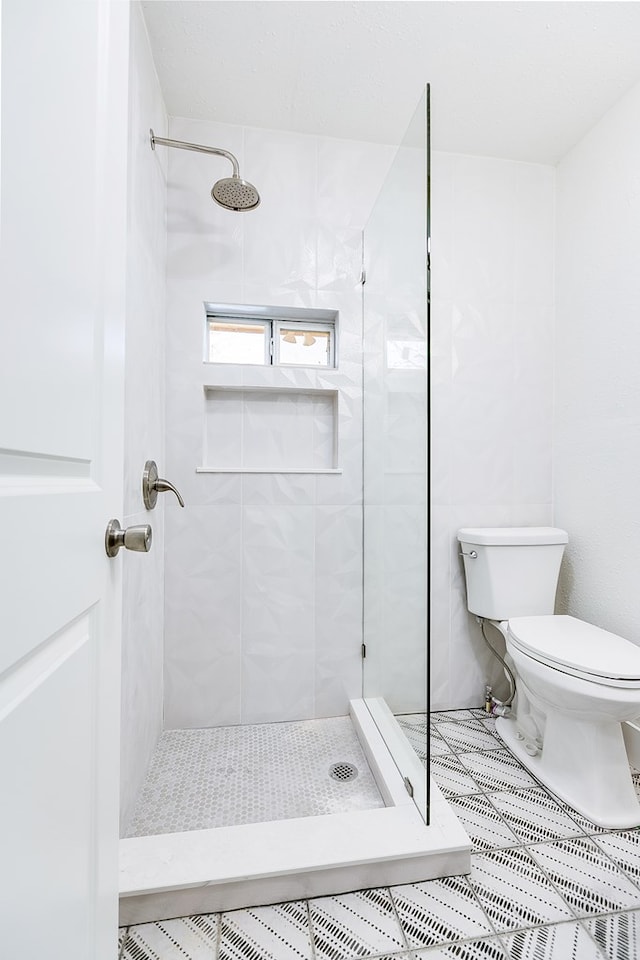 bathroom featuring tiled shower and toilet