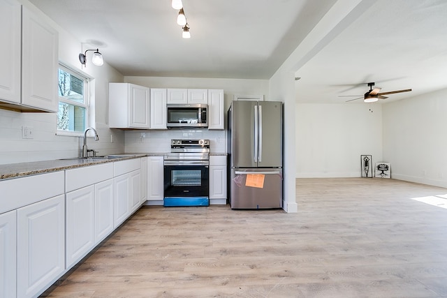 kitchen featuring stainless steel appliances, sink, decorative backsplash, and white cabinets