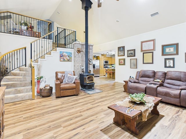675 Buffalo Ln, San Angelo, TX 76901 - living room featuring a wood stove, wood finished floors, high vaulted ceiling, stairway, and ornamental molding