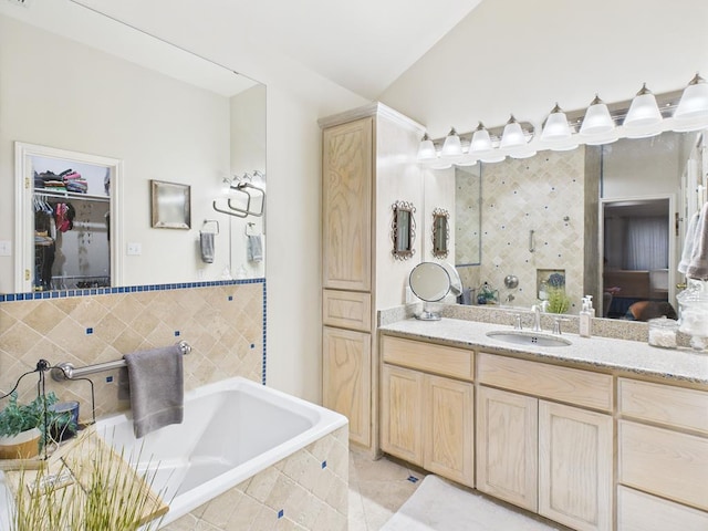 675 Buffalo Ln, San Angelo, TX 76901 - bathroom featuring vanity, tiled tub, a walk in closet, and tile patterned flooring