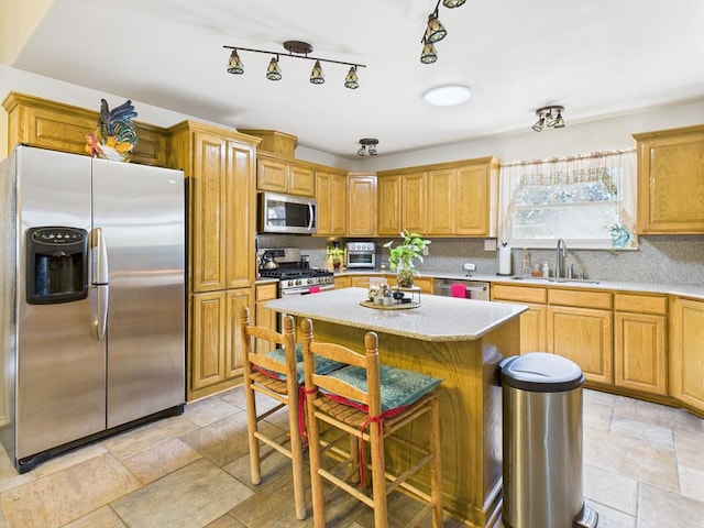 675 Buffalo Ln, San Angelo, TX 76901 - kitchen with appliances with stainless steel finishes, a kitchen island, stone tile floors, tasteful backsplash, and a breakfast bar