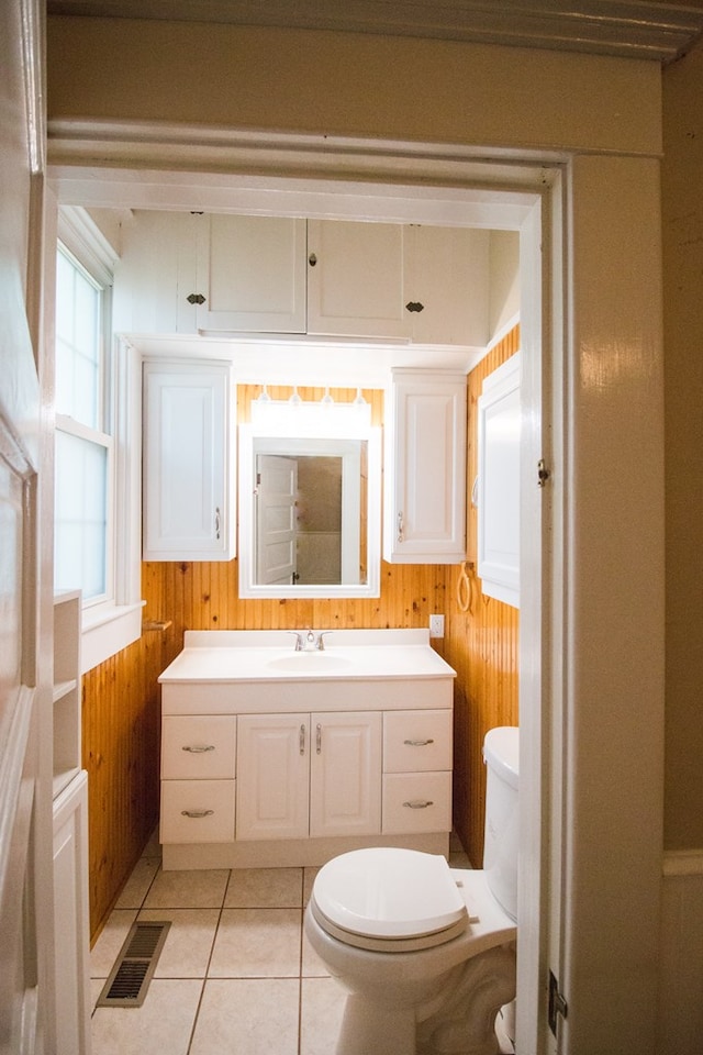 bathroom featuring vanity, toilet, tile patterned flooring, and wood walls