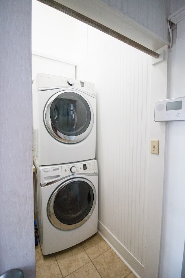 washroom with stacked washer / drying machine and light tile patterned floors