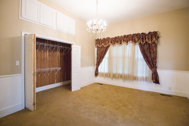 carpeted spare room with an inviting chandelier