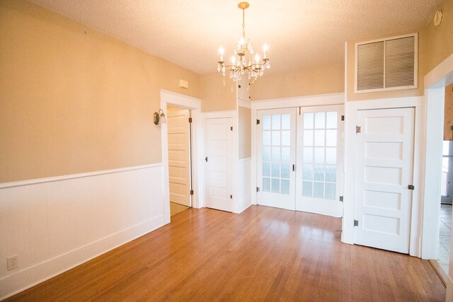 spare room featuring hardwood / wood-style flooring, french doors, and a chandelier