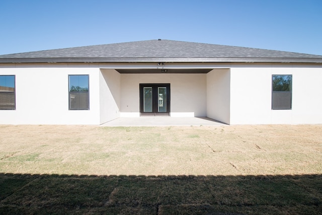 rear view of house featuring a yard, french doors, roof with shingles, and stucco siding