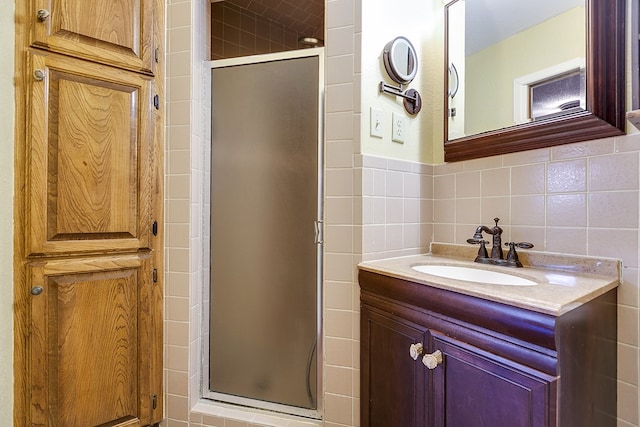 bathroom featuring vanity, a shower with door, and tile walls