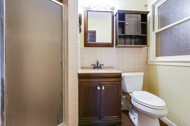 bathroom featuring vanity, tasteful backsplash, a shower with shower door, and toilet