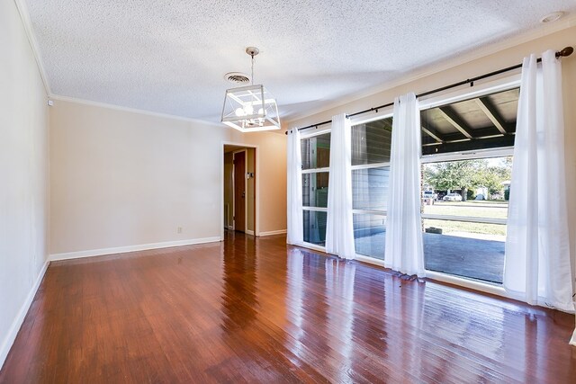 spare room with ornamental molding, dark hardwood / wood-style floors, a textured ceiling, and a chandelier