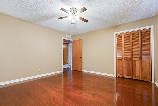 unfurnished bedroom featuring ceiling fan, dark hardwood / wood-style floors, a textured ceiling, and a closet