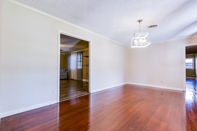 unfurnished room featuring dark hardwood / wood-style flooring, a notable chandelier, ornamental molding, and a textured ceiling