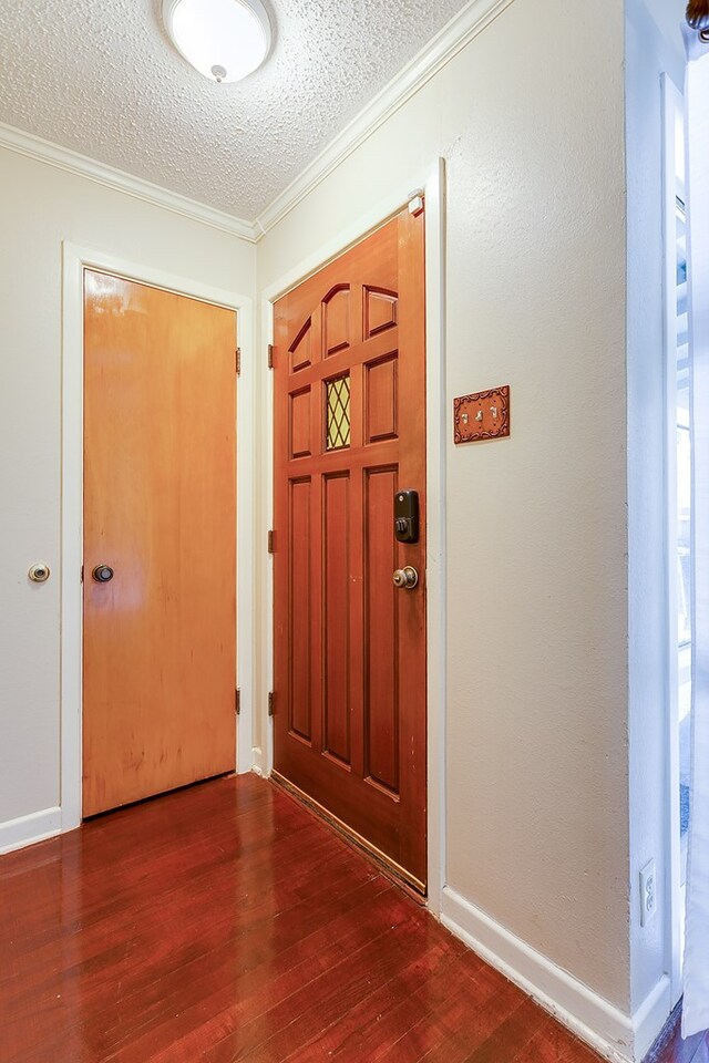 entryway featuring ornamental molding, dark hardwood / wood-style floors, and a textured ceiling