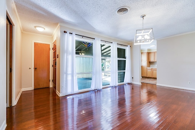 spare room with dark hardwood / wood-style flooring, ornamental molding, a textured ceiling, and an inviting chandelier