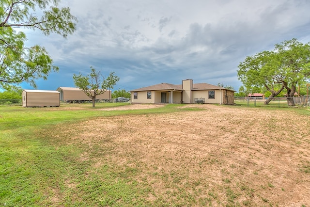 back of property with fence, a chimney, and a lawn