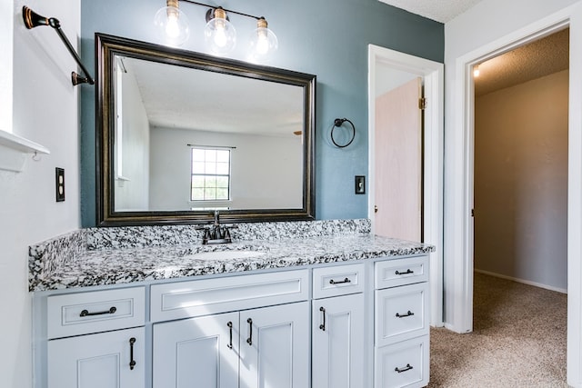 bathroom with a textured ceiling, baseboards, and vanity