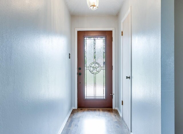 doorway to outside with baseboards and wood finished floors