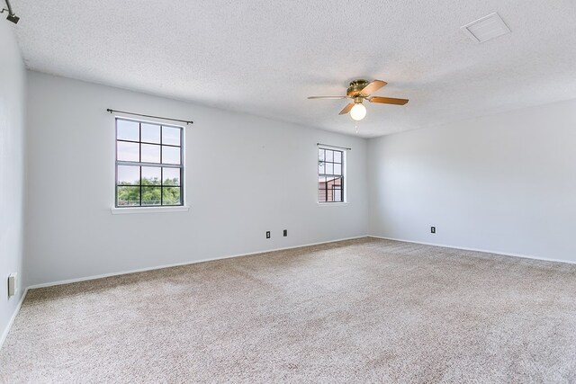 carpeted empty room with baseboards, a ceiling fan, a textured ceiling, and visible vents