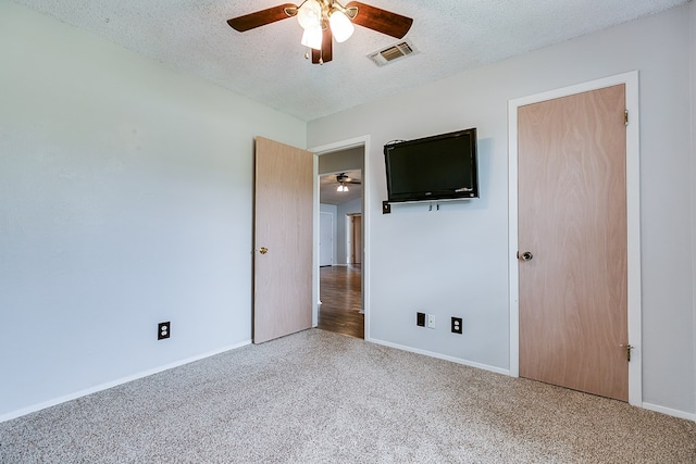unfurnished bedroom with ceiling fan, a textured ceiling, visible vents, baseboards, and carpet