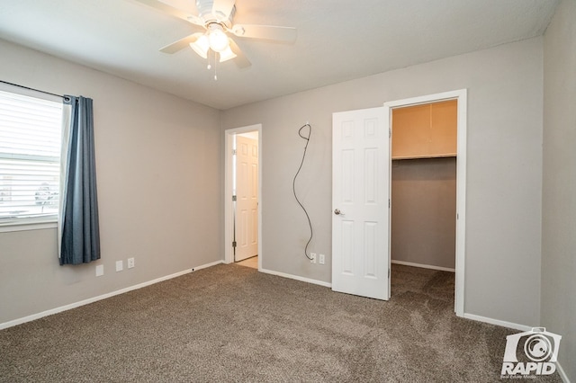 unfurnished bedroom featuring a spacious closet, baseboards, carpet, and a ceiling fan