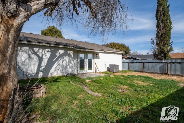 rear view of house featuring a yard, central AC, french doors, and fence