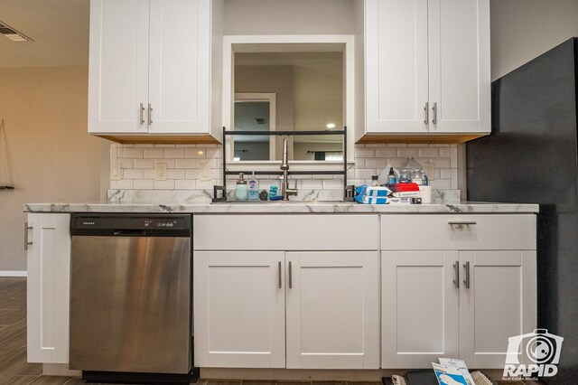 kitchen with visible vents, white cabinetry, a sink, stainless steel dishwasher, and tasteful backsplash