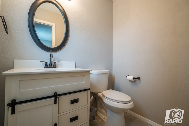 half bathroom with tile patterned floors, toilet, vanity, and baseboards