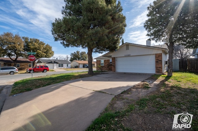 view of front of house featuring fence, an attached garage, a chimney, concrete driveway, and brick siding