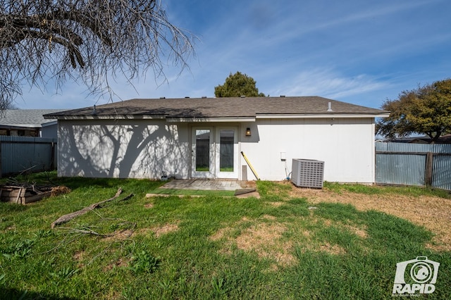 rear view of property with french doors, a lawn, central AC unit, and fence