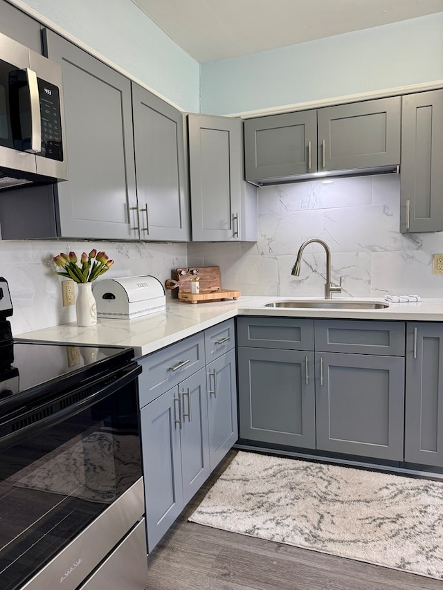 kitchen with gray cabinetry, sink, dark wood-type flooring, and appliances with stainless steel finishes