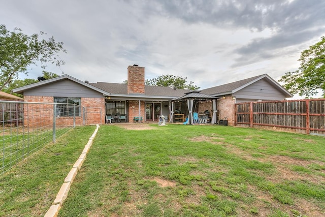 3626 Willowbrook Dr, San Angelo, TX 76904 - back of house with a chimney, a lawn, brick siding, a gazebo, and a fenced backyard