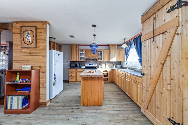 kitchen featuring stainless steel electric stove, decorative light fixtures, sink, white refrigerator, and a center island