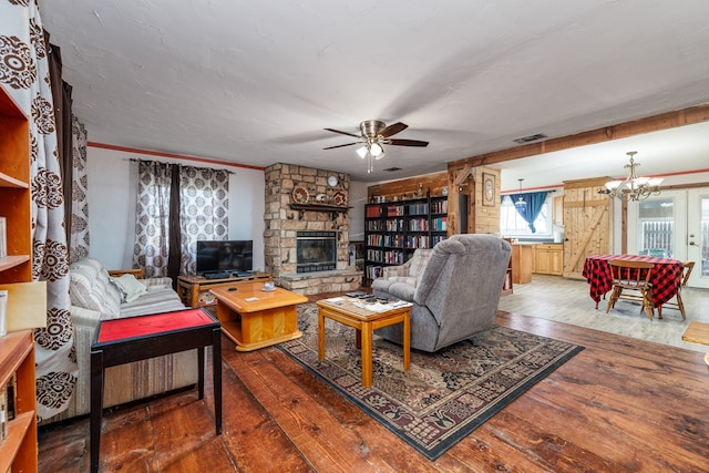 living room with hardwood / wood-style floors, ceiling fan with notable chandelier, a fireplace, and ornamental molding