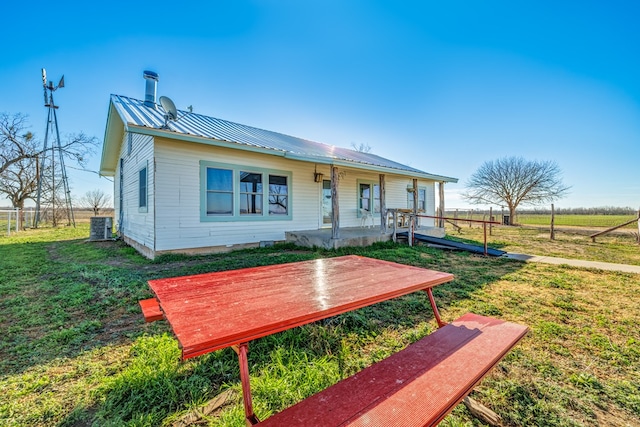 view of front of home with cooling unit, a front lawn, and covered porch