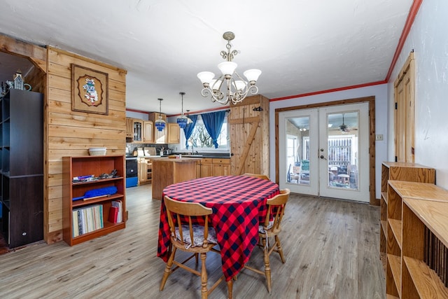 dining space featuring french doors, crown molding, sink, and light hardwood / wood-style flooring