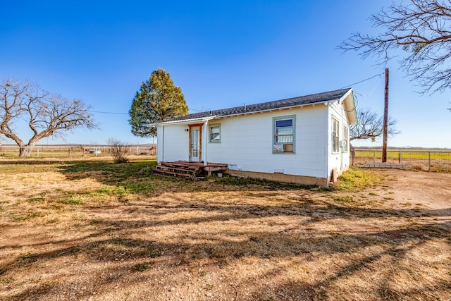 rear view of house with a lawn and a rural view