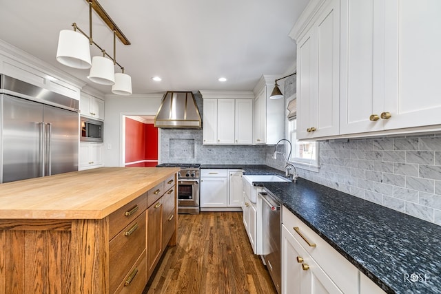 1322 S Monroe St, San Angelo, TX 76901 - kitchen with built in appliances, wall chimney exhaust hood, a sink, wooden counters, and dark wood finished floors