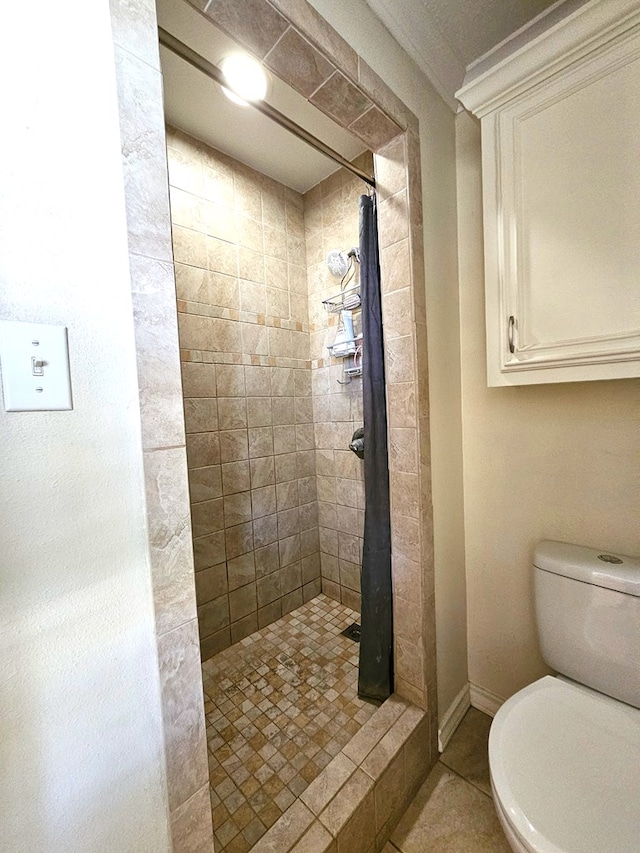 bathroom with crown molding, tile patterned floors, toilet, and tiled shower