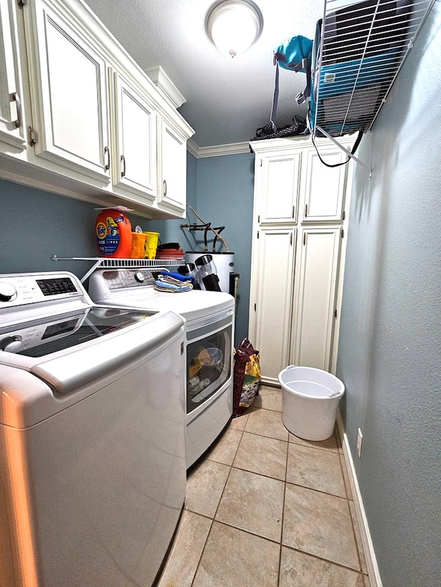 clothes washing area with cabinets, ornamental molding, washer and dryer, and light tile patterned floors