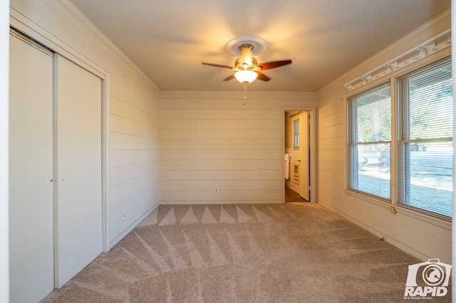 unfurnished bedroom with crown molding, ceiling fan, carpet flooring, and a closet