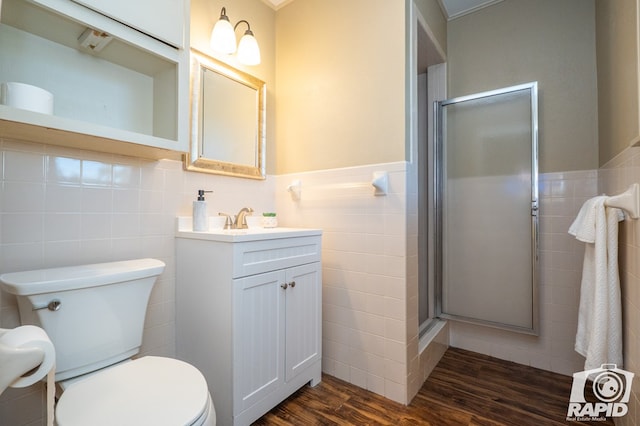 bathroom with hardwood / wood-style flooring, tile walls, vanity, toilet, and walk in shower