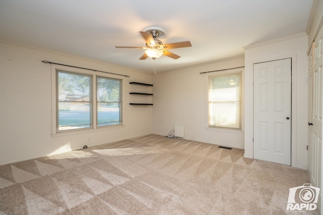 unfurnished room with ceiling fan, ornamental molding, plenty of natural light, and light carpet