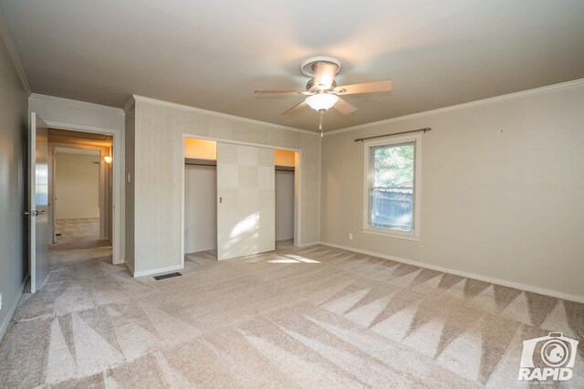 unfurnished bedroom featuring crown molding, light carpet, ceiling fan, and a closet