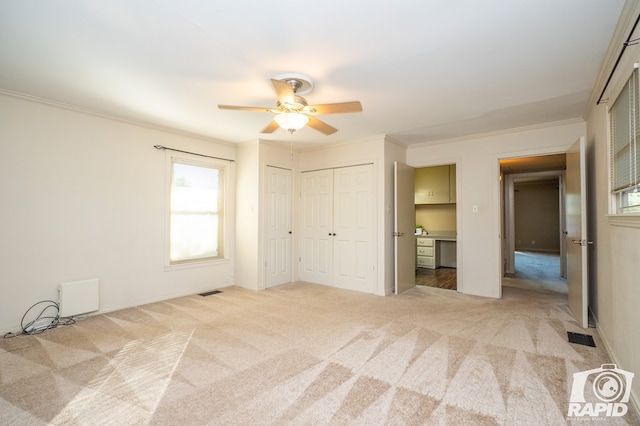 unfurnished bedroom with crown molding, ceiling fan, and light colored carpet